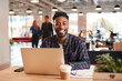 © Monkey Business - Portrait Of Smiling Businessman Sitting At Desk With Laptop In Modern Open Plan Office