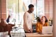 © Monkey Business - Businessman And Businesswoman Having Informal Meeting By Desk In Modern Open Plan Office