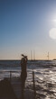 © Vimaki - Silueta de mujer en un puente de madera al atardecer en el mar