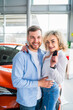 © Andrii  - Happy couple in car dealership on the background of their new car