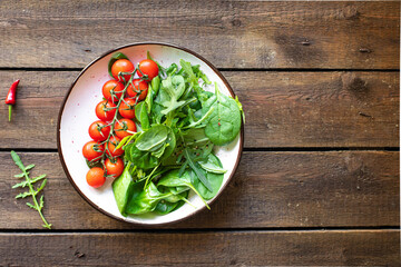 tomato salad cherry veggie green leaves fresh mix greens spinach, arugula, lettuce ingredient on the table healthy food meal copy space food background keto or paleo diet  