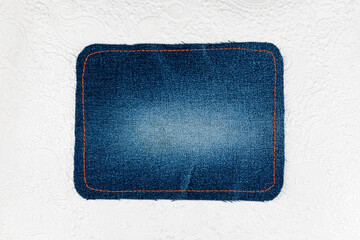 denim fabric patch lies on the white leather. top view.