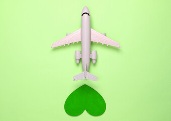 Sticker - Air travel lover. Airplane figurine with green heart on green pastel background. Top view