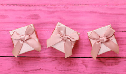 Poster - Gift boxes with bows on a pink wooden background. Top view