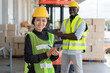 © Supachai - Young Asian woman with man worker in safety vest and yellow helmet working at shipment at warehouse factory
