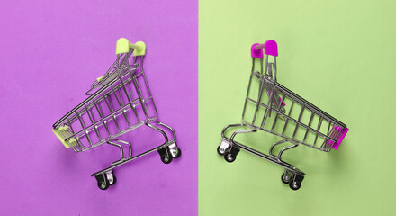 Two mini supermarket trolleys on colored background. Shopping concept. Top view. Minimalism