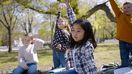 Wall Mural - Small children sitting outdoors in city park, learning group education concept.