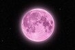 Full pink supermoon halo glowing surrounded by stars on black night sky background