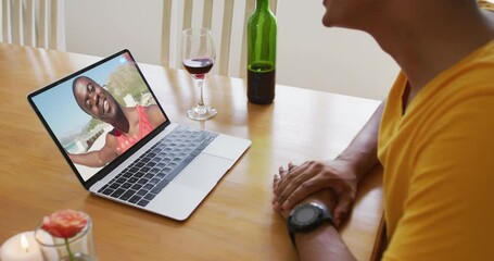 Poster - Mixed race man sitting at table using laptop making video call with male friend