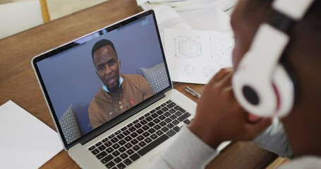 Sticker - African american male college student holding notes while having a video call on laptop at home