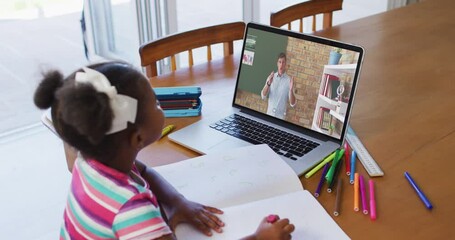 Sticker - African american girl doing homework while having a video call with male teacher on laptop at home