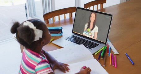 Wall Mural - African american girl doing homework while having a video call with female teacher on laptop at home