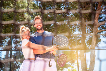 man and a woman happily hug each other after a game of padel in a sunny day