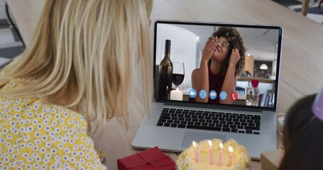 Poster - Caucasian mother and daughter sitting at table using laptop having birthday video call