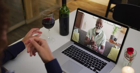 Sticker - Mid section of african american woman drinking wine while having a video call on laptop at home