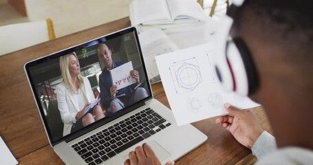 Sticker - African american male college student holding notes while having a video call on laptop at home