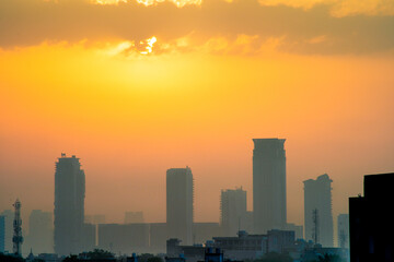 Wall Mural - cloudy dusk dawn shot with the sun hidden and fog obscured sky scrapers multi story buildings of cityscape of gurgaon, mumbai, bangalore during the monsoons in India