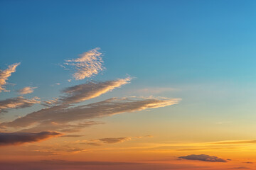 calm golden blue sunset sky with few long clouds at left. the rays of the setting sun gilded the clo
