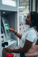 African american woman inserting credit card and withdrawing cash at ATM