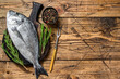 Raw Sea bream or dorado sea fish with spices and herbs on a cutting board. wooden background. Top view. Copy space
