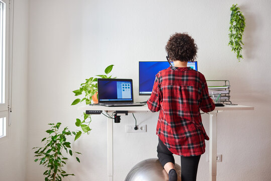 unrecognizable woman teleworking at an adjustable standing desk