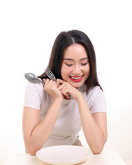 Wall Mural - Beautiful young south east Asian woman pretend acting posing holding empty fork spoon in hand eat taste look see white plate on table white background smile happy