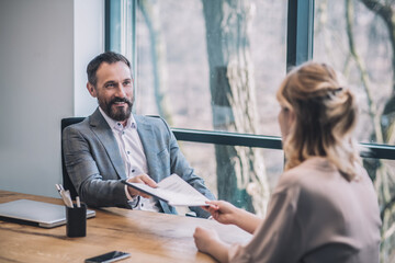 Business man taking documents from female assistant