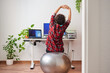 © Jose - Woman stretches while working out sitting on a fitball