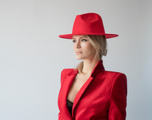 Portrait Of A Beautiful Woman Wearing Red Hat And In Red Jacket On A Gray Background