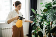© Beznika - woman spraying plants at home