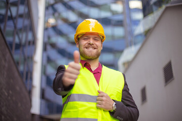 Wall Mural - Smiling engineer standing on the street. Cloe up. Thumb up.