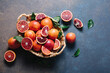 Whole and sliced blood oranges in a basket on blue table background. Flat lay, top view, copy space.
