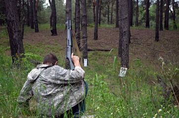 Wall Mural - Man with 12-gauge rifle (pump action shotgun). Unformal shooting range near Kiev.