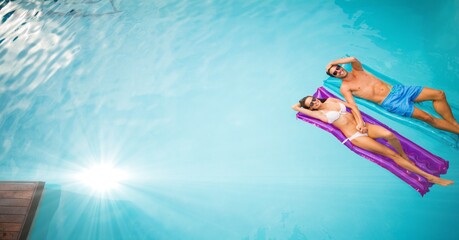 Wall Mural - Composition of couple lying on inflatables in swimming pool with glowing light and copy space