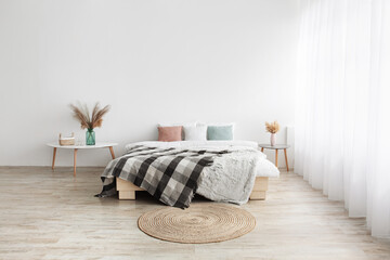 Wall Mural - Bed with pillows and blanket, round carpet, tables with dry plants in vases on wooden floor