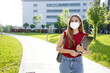 Business girl with protective mask walks holding folders in her hands with office buildings on the background