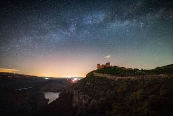 Wall Mural - Night landscape arch of the Milky Way over a castle. Chirel Castle, Valencia. Beautiful views of the Milky Way above a castle on a mountain hill surrounded by a large lake