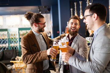 Wall Mural - Happy young businessmen drinking beer and talking at pub after work