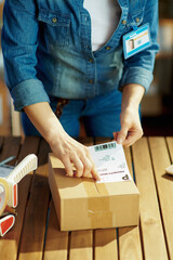 Modern female in office applying shipping label to parcel