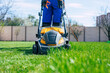 © My Ocean studio - Young man mows the lawn using an electric lawn mower in a special worker suit near a large country house in the backyard