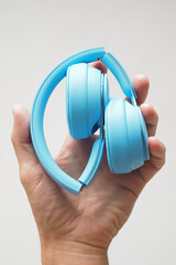 Close-up. Folded blue headphones in hand.