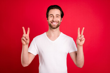 Poster - Photo of funny young brown hairdo man show v-sign wear white t-shirt isolated on vivid red color background