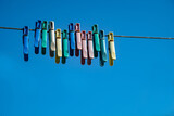 Fototapeta  - Multicolored clothespins on a rope against the blue sky.