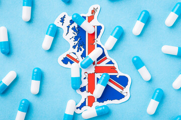 Many blue and white pills capsules on flag of Great Britain. Concept of medicine in Great Britain