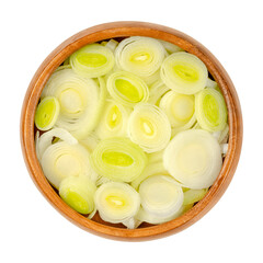 Wall Mural - Leek slices, in a wooden bowl. Chopped leaf sheaths and cross sections of Allium ampeloprasum, a crunchy and firm vegetable with mild and onion-like taste. Close-up from above, over white, food photo.