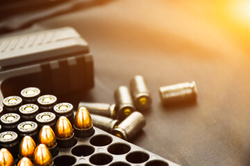 9mm bullet shells placed near 9mm pistol on black leather background, soft and selective focus.