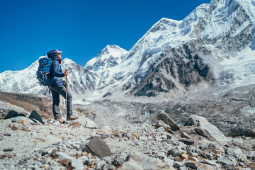 Wall Mural - Young hiker backpacker female taking brake in hike walking enjoying Khumbu Glacier. High altitude Everest Base Camp route near Gorakshep,Nepal. Nuptse 7861m on background. Active vacations concept