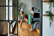 © grigvovan - Slender mature woman changes clothes near window in loft apartment, her sister helps her.