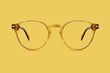 © amedeoemaja - beige and golden plastic color eye glasses isolated on yelloww background, ideal photo template for display or advertising sign or for a web banner
