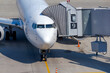 © Андрей Рыков - White commercial airplane docked on apron outside airport terminal with passenger boarding bridge. Sunny day. No people. Transportation theme.
